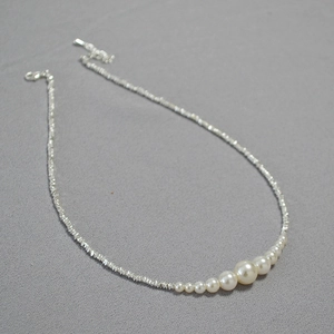 Detail of silver-style irregular bead necklace with gradient pearls and extension chain