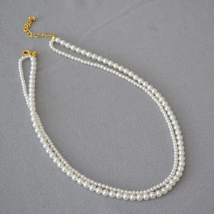 Detail of double-layer pearl necklace showing golden lobster clasp and adjustable chain