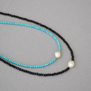 Close-up of turquoise and black spinel beaded necklaces with baroque pearls and gold spacers