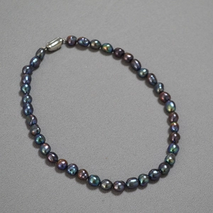 Macro shot of peacock green Baroque pearls necklace with silver oval clasp detail