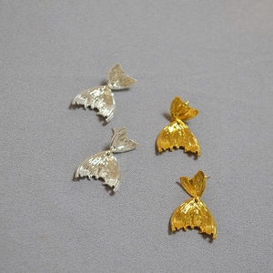 Macro view of gold and silver fishtail earrings showing detailed vertical texture