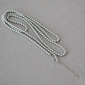 Gros plan d'un collier de perles grises avec fermoir mousqueton argenté et extension