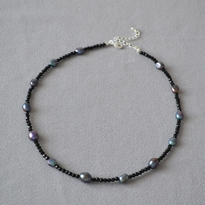 Dettaglio collana con perle di spinello nero e perle barocche verde pavone cangiante