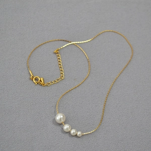 Collier minimaliste en laiton doré orné de quatre perles blanches en dégradé élégant