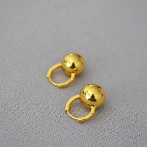 Minimalist gold ball earrings with polished mirror finish on deep grey textured background