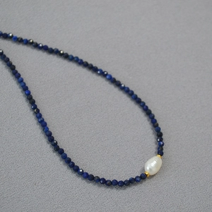 Macro detail of turquoise beads with a baroque pearl pendant on a gold plated necklace