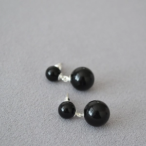 Détail de boucles d'oreilles en argent 925 avec doubles perles en agate noire sur fond gris