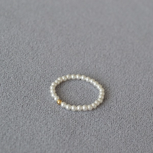 Minimalist 14K gold filled bead and small white pearl ring on dark textured fabric background