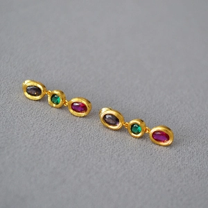 Detail of vintage gold-plated drop earrings featuring three colorful oval gemstones