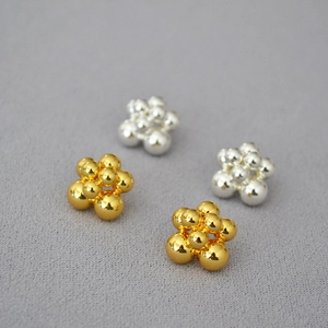 Macro shot of minimalist polished gold and silver cluster bead stud earrings
