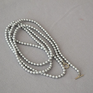 Sautoir en perles gris argenté avec fermoir OT doré sur fond en maille grise