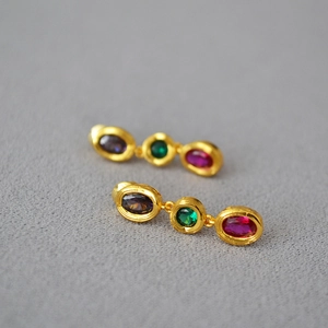Macro shot of three-tier vintage gold earrings with purple, green and rose gems