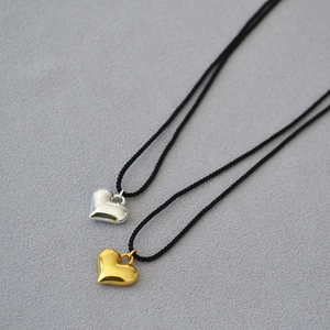 Detail of 3D heart pendants in gold and silver finish with adjustable black cord