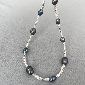 Macro detail of dark Tahitian style pearls and faceted silver metallic spacers on a necklace