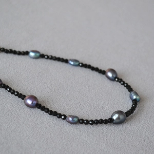 Dettaglio ravvicinato della collana con spinello nero e perle barocche iridescenti