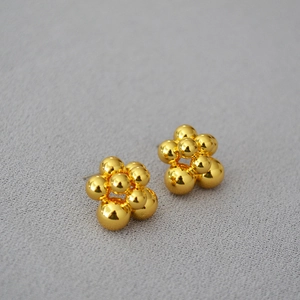 Detail of gold cluster earrings featuring a polished berry floral bead design