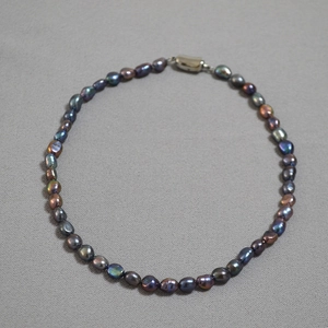 Macro detail of Tahitian green baroque pearls showing colorful luster and silver clasp