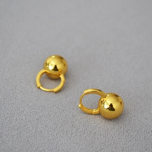 Detail of minimalist gold bead hoop earrings showing smooth polished metallic finish