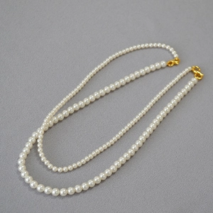 Detail of elegant white pearls layered necklace with gold-toned double strand clasp closure