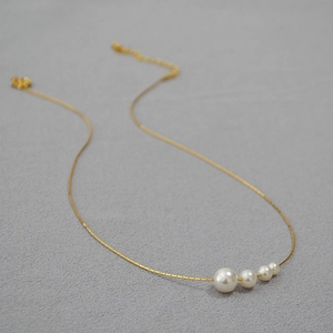 Détail d'un collier en chaîne dorée avec perles dégradées et fermoir réglable