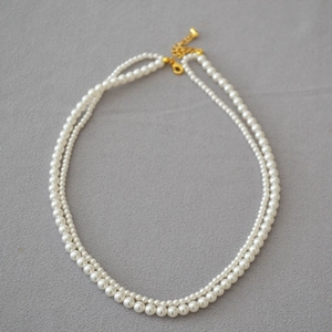 Macro detail of double-layer pearl necklace with golden lobster clasp and extension chain