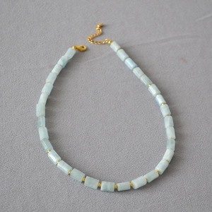 Detail of light blue cylindrical stone beads and golden spacers on a vintage necklace