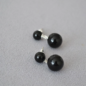 Vue macro de boucles d'oreilles minimalistes à double perle noire avec finition brillante