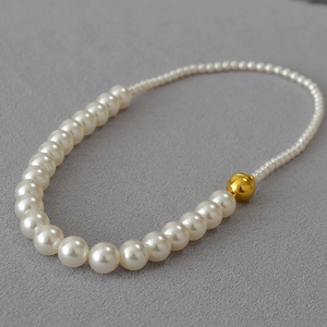 Dettaglio di collana di perle graduate con una sfera dorata decorativa e chiusura magnetica