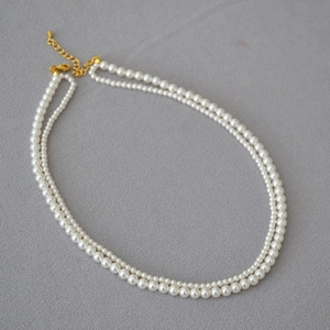 Detail of double-layer faux pearl necklace with gold-plated lobster clasp and extension chain
