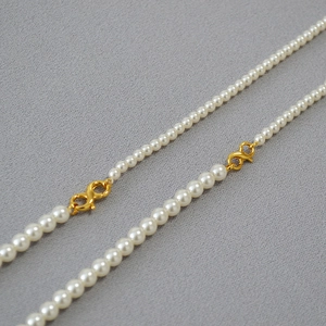 Detail of high-luster round pearl necklace with golden infinity style connector clasp