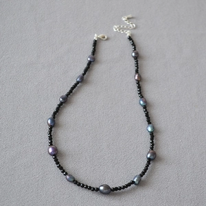 Dettaglio di perline di spinello nero e perla di Tahiti verde su collana artigianale