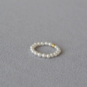 Macro shot of minimalist 14K gold-filled bead and delicate white pearls elastic ring