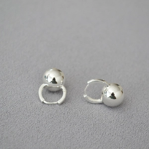 Detail of silver polished ball drop earrings on gray textured background