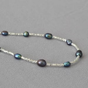 Macro detail of dark baroque pearls and faceted silver beads on an irregular necklace