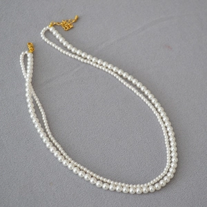 Detailed macro view of white double-layer faux pearl necklace with gold clasp and chain