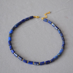 Detail of beaded necklace with blue cylindrical natural stones and golden spacer beads