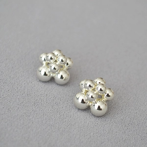 Macro shot of silver plated brass flower earrings with polished metallic beads and mirror finish