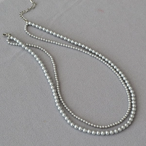 Detail view of double-layer faux pearl necklace with silver lobster clasp and extension chain