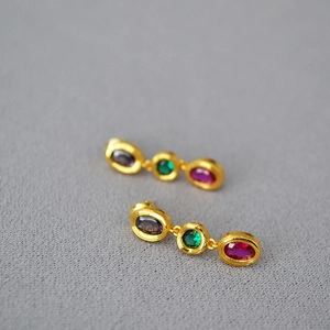 Detail of vintage brass earrings with colorful purple green and red faceted gemstones