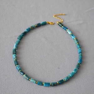 Detail of blue natural stone cylinder beads and gold spacer beads on a vintage necklace