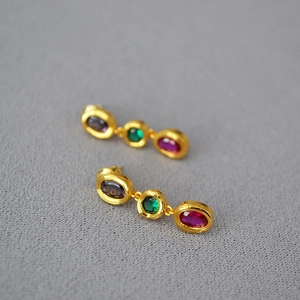 Macro detail of vintage gold earrings with triple-layered colorful gemstone inlays