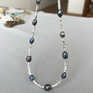 Macro shot of dark Tahitian style pearls and irregular silver beads on a short necklace