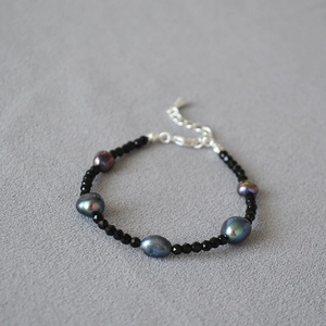 Dettaglio di perle di spinello nero e perle di pavone su una collana elegante