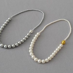 Dettaglio collana di perle bianche e grigie con chiusura magnetica a sfera dorata