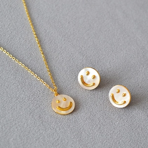Dettaglio del set di gioielli con faccina sorridente dorata e madreperla cangiante