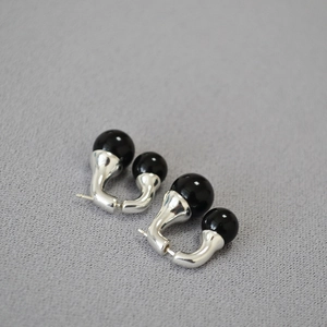 Detailed view of silver U-shaped earrings with black agate beads on grey background