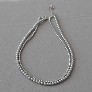 Detailed close-up of double-layer silver bead necklace with adjustable lobster clasp and chain