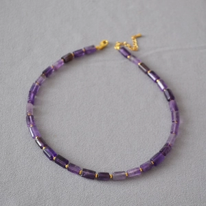 Detail of natural purple amethyst cylinder beads necklace with golden spacer beads