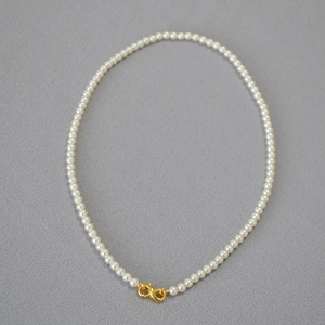 Detailed shot of white round pearls with a golden infinity-shaped metal clasp