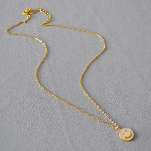 Collana con faccina sorridente dorata, ciondolo in madreperla e catena regolabile